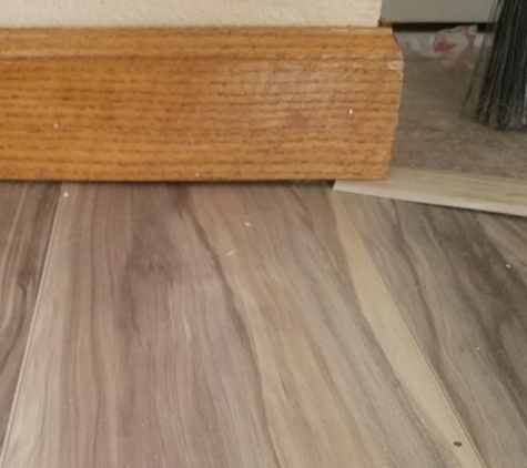 Carpet Wise Inc - Longmont, CO. Here is transition UNDER my baseboard - causing it to slope. The weirdo they sent to fix these wanted to cut a notch out in my baseboard!!