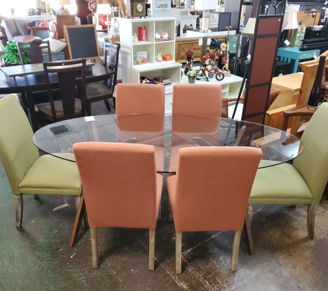 Better Than New Pre Owned Furniture - Longwood, FL. picture of an oval glass dining table with 4 orange upholstered chairs on the long sides and 2 green chairs at the head and foot